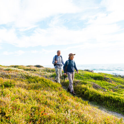 couple de personnes âgées se promenant le long des dunes d'une plage