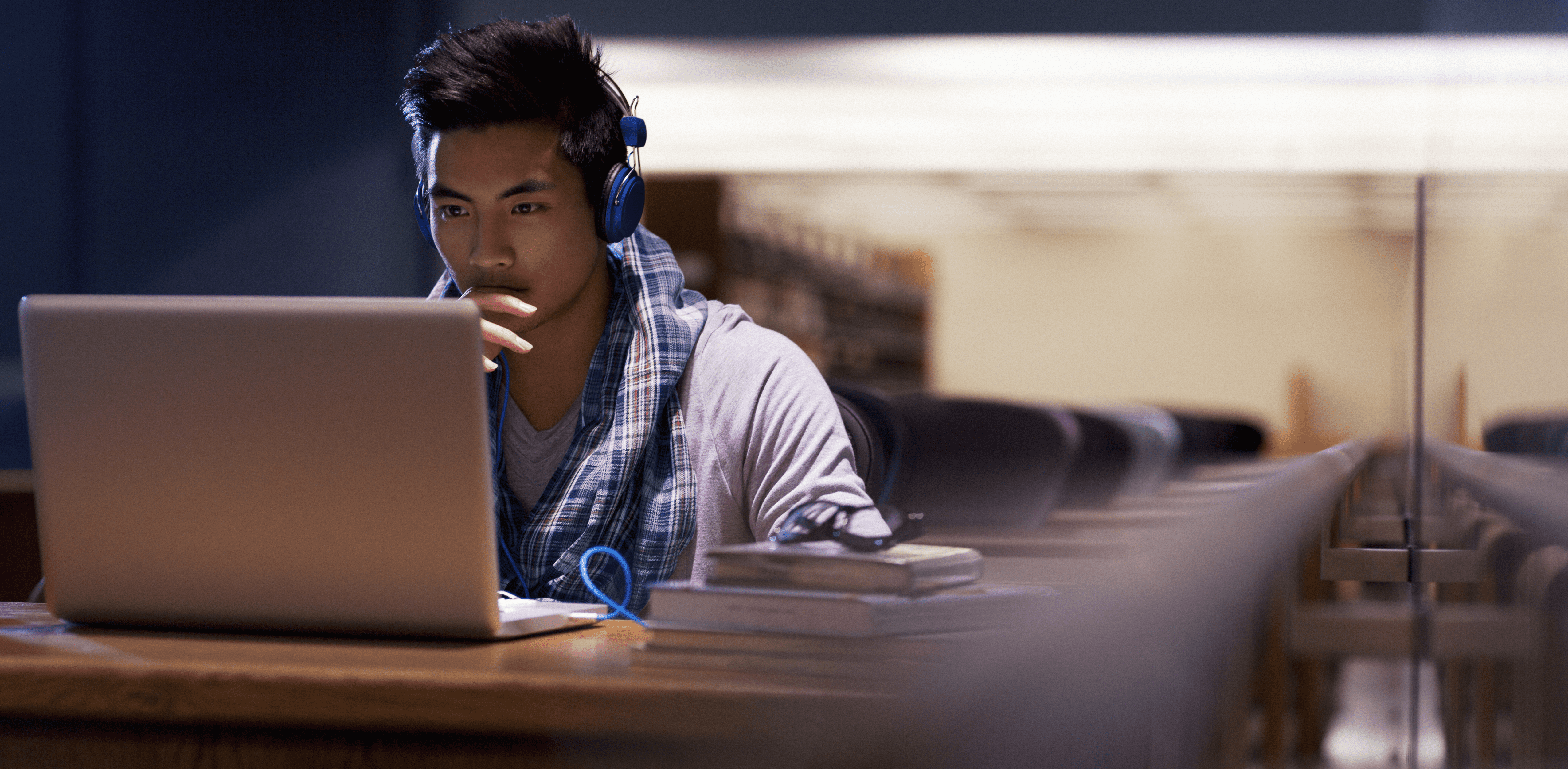 jeune homme sur ordinateur portable dans la bibliothèque