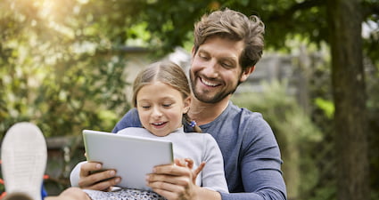 Homme et sa fille devant leur tablette tactile