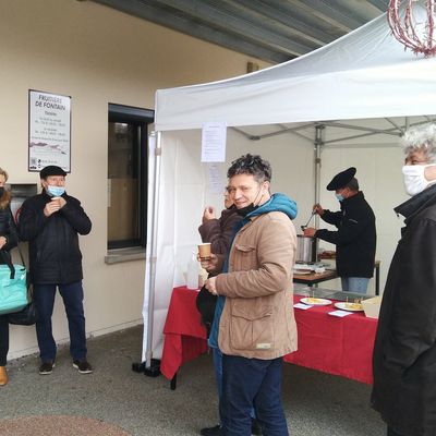 Les clients patientent en dégustant un vin chaud servi par l'un des producteurs de la fruitière.