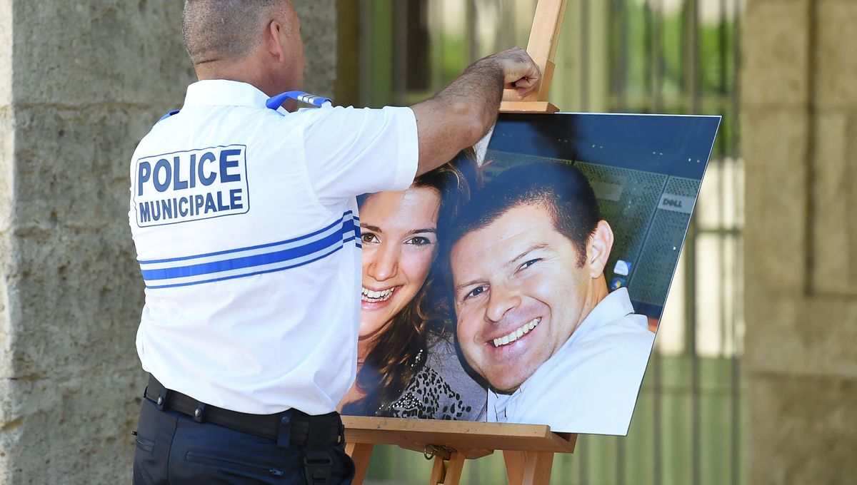 Un policier municipal accroche le portrait de Jean-Baptiste Salvaing et Jessica Schneider, assassinés à Magnanville (Yvelines) le 13 juin 2016