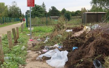 Creil (Oise), le 11 septembre. Plastique, matériaux mêlés aux déchets verts... Les jardins familiaux font régulièrement l'objet de dépôts sauvages, même au pied du panneau d'interdiction situé à l'entrée. LP/Florent Heib