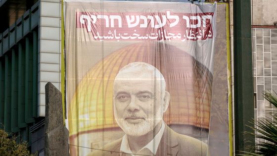 Deux hommes accrochent à un immeuble de Téhéran (Iran), le 31 juillet 2024, une banderole géante représentant le chef du Hamas, Ismail Haniyeh, qui a été tué.