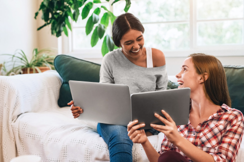 Deux jeunes filles souriantes travaillant sur leur ordinateur connecté en VDSL