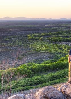 A hiker looks over San Pedro Riparian NCA with the sun shining across the landscape. Photo by Bob Wick.