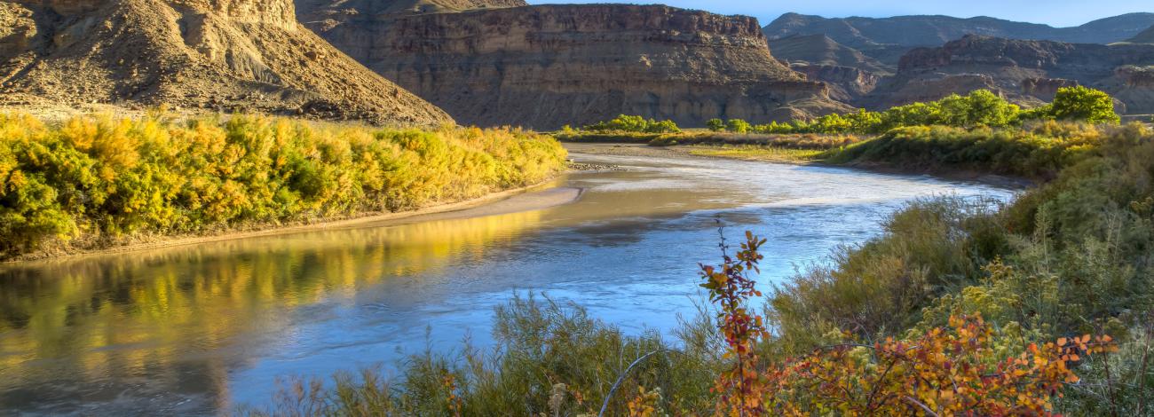 A river winds through a fall-colored landscape with rock formations rising in the background.