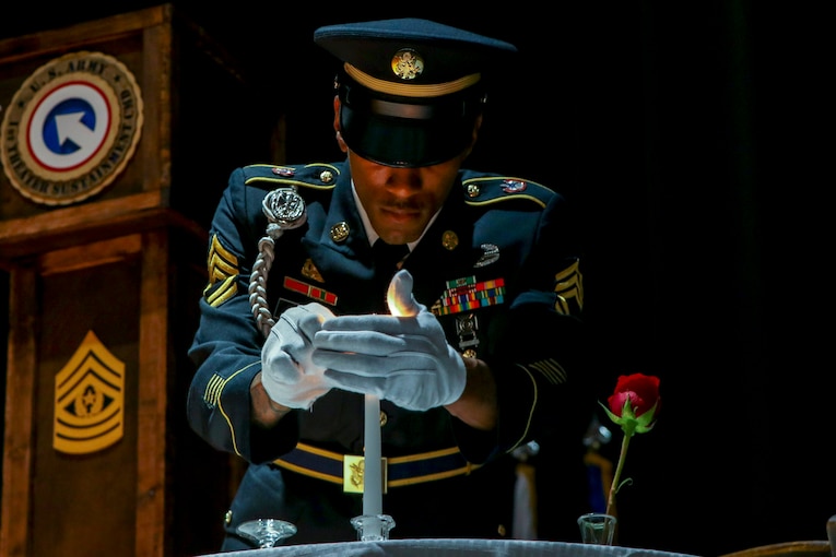 Army Sgt. 1st Class Anthony Bynum lights a candle to recognize and honor prisoners of war and missing in action service members