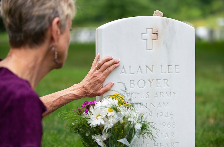 Judi Boyer-Bouchard touches the headstone for her brother, Sgt. 1st Class Alan Boyer, during a visit to Arlington National Cemetery, Va.