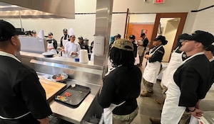 chef at left circled by 20 students in the CIA kitchen