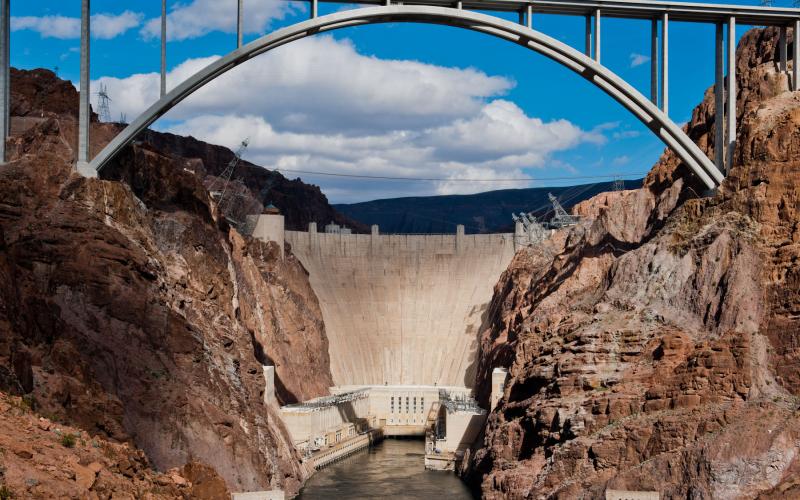 Hoover Dam and the bypass bridge under a partially-cloudy sky.