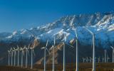 Wind turbines in front of a snowy mountain range.