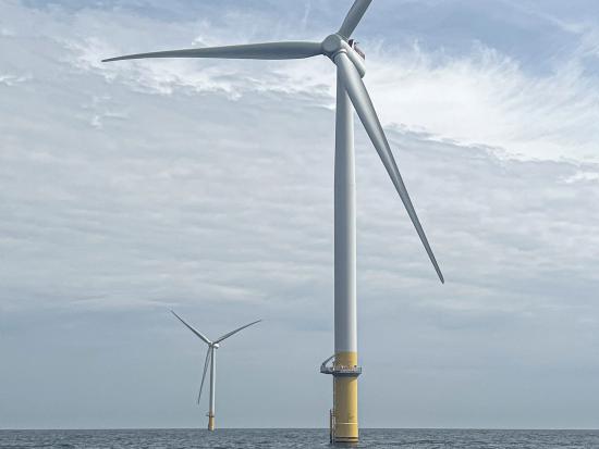 Two wind turbines in the ocean.