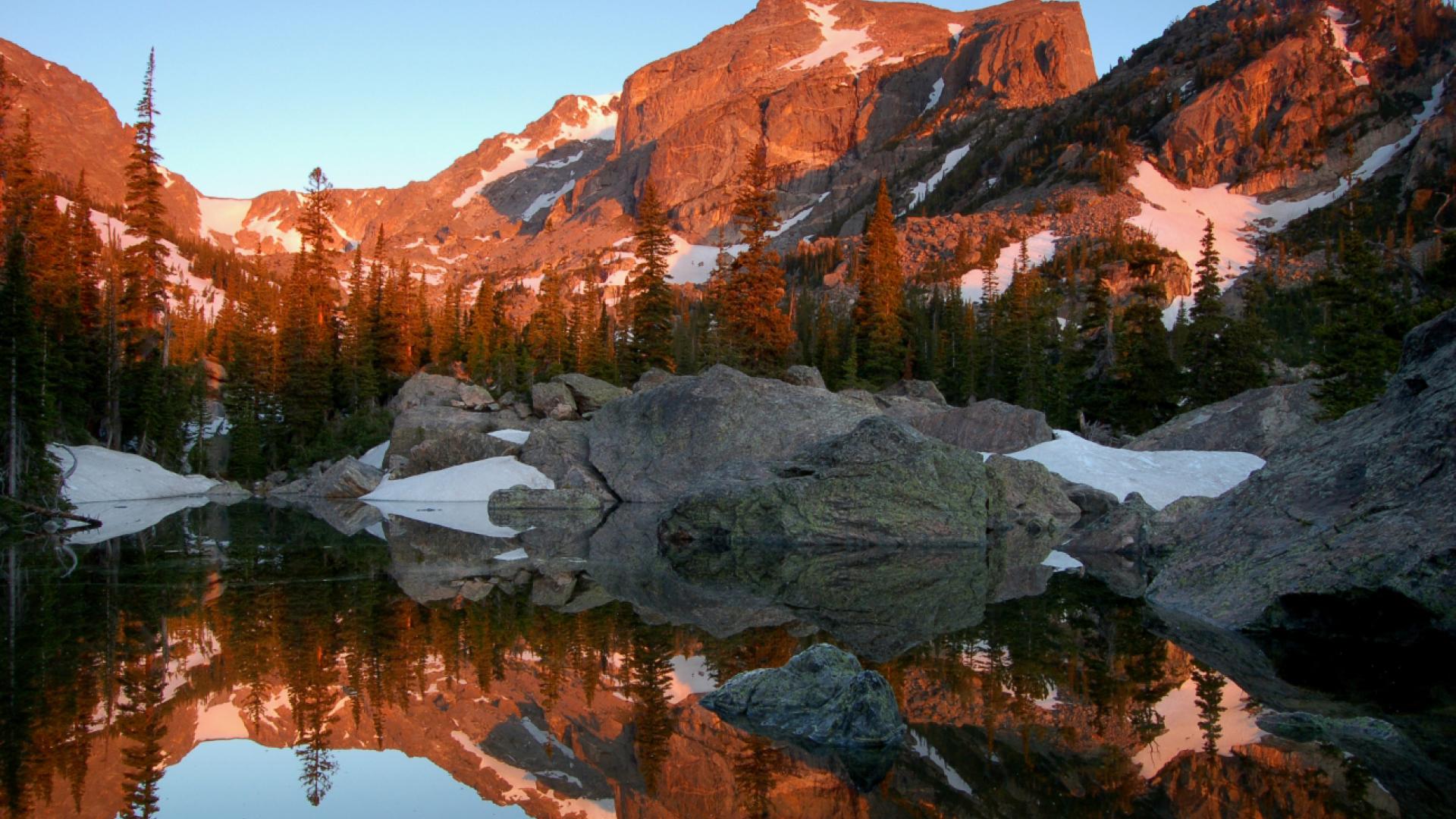 Snow covered mountains and evergreens reflected in a lake