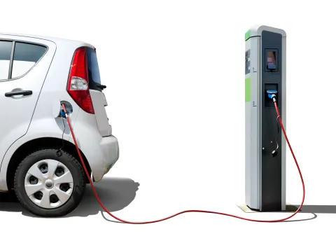 An electric vehicle is parked by a green charging station