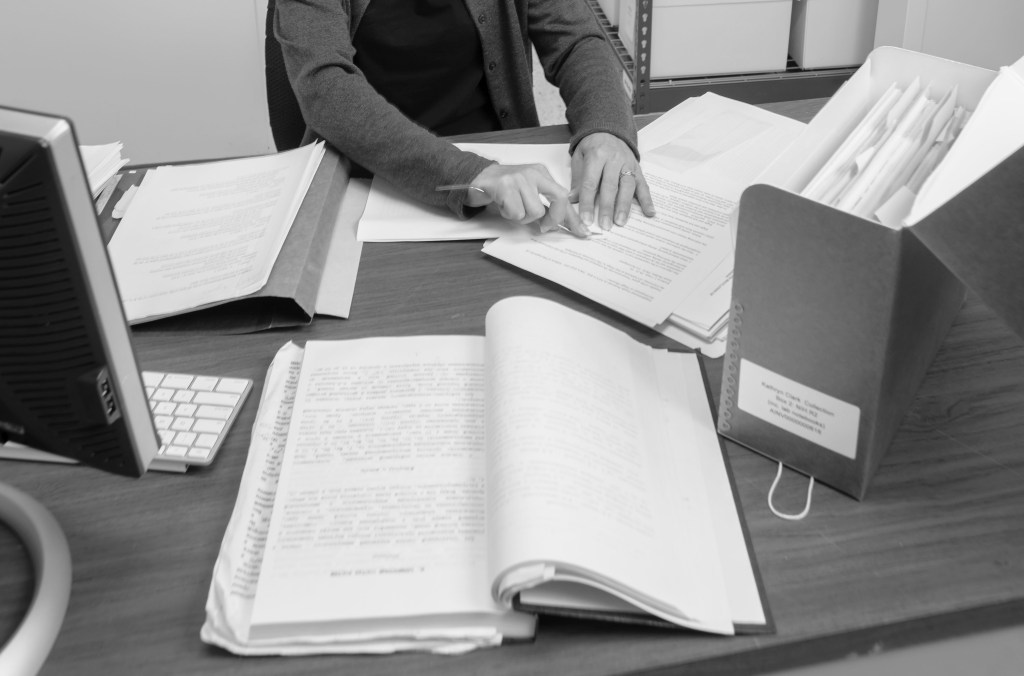 Archival documents on table and hands of archivist performing preservation