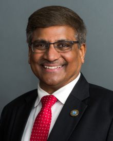 NSF's director, wearing glasses and a red tie, smiling.