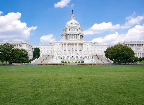 United States Capitol Building, grass in the foreground and blue sky in the background.