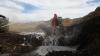 Heavy equipment digs into brown ground among extinguishing liquids