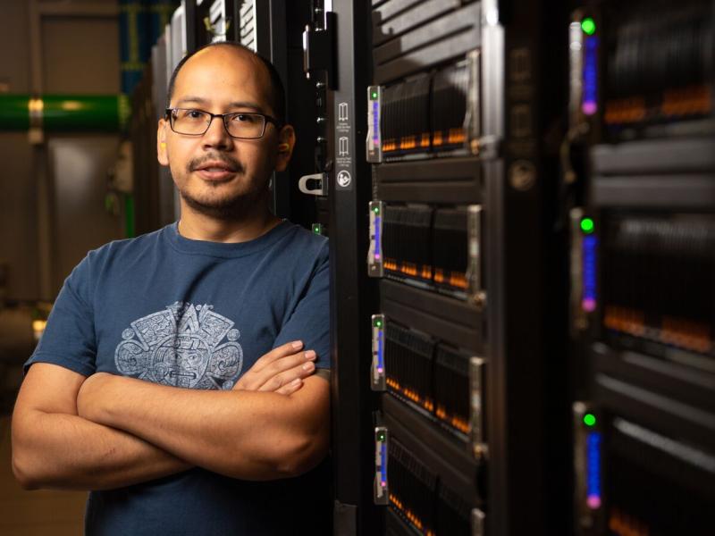 Photograph of Daniel Mejia Rodriguez standing near a powerful computer.