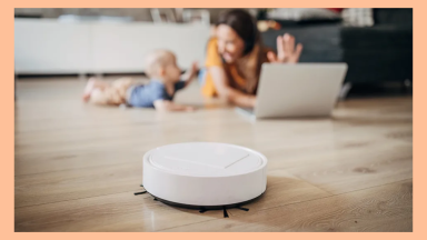 Robot vacuum cleaning the floor in front of a mother and child