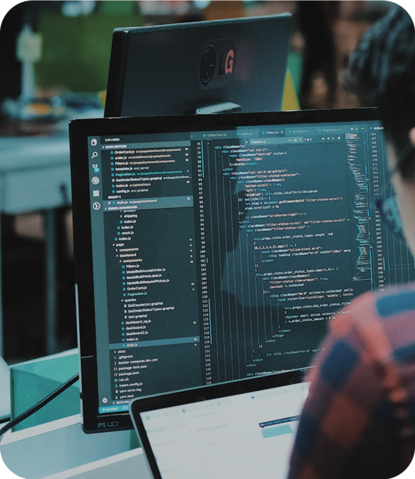 A person coding on a computer with a second monitor displaying code.