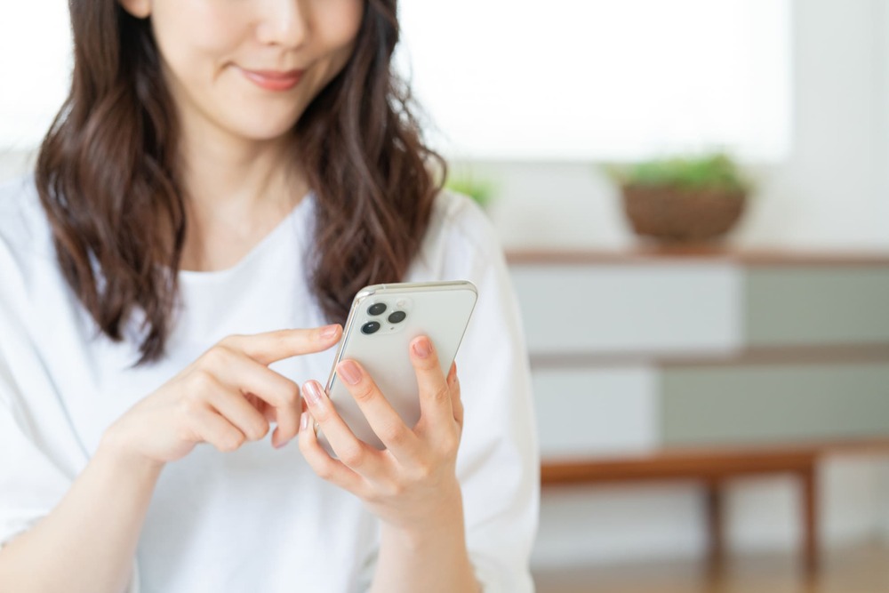 スマホを触る笑顔の女性