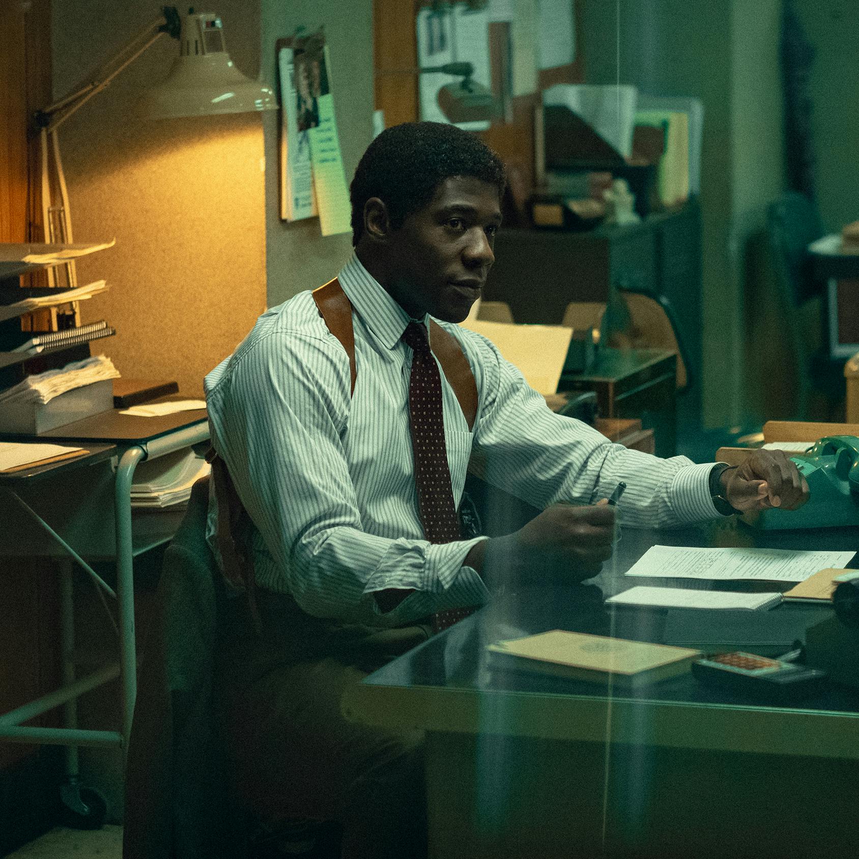 Detective Michael Ledroit (McKinley Belcher III) looks solemn at a police desk.