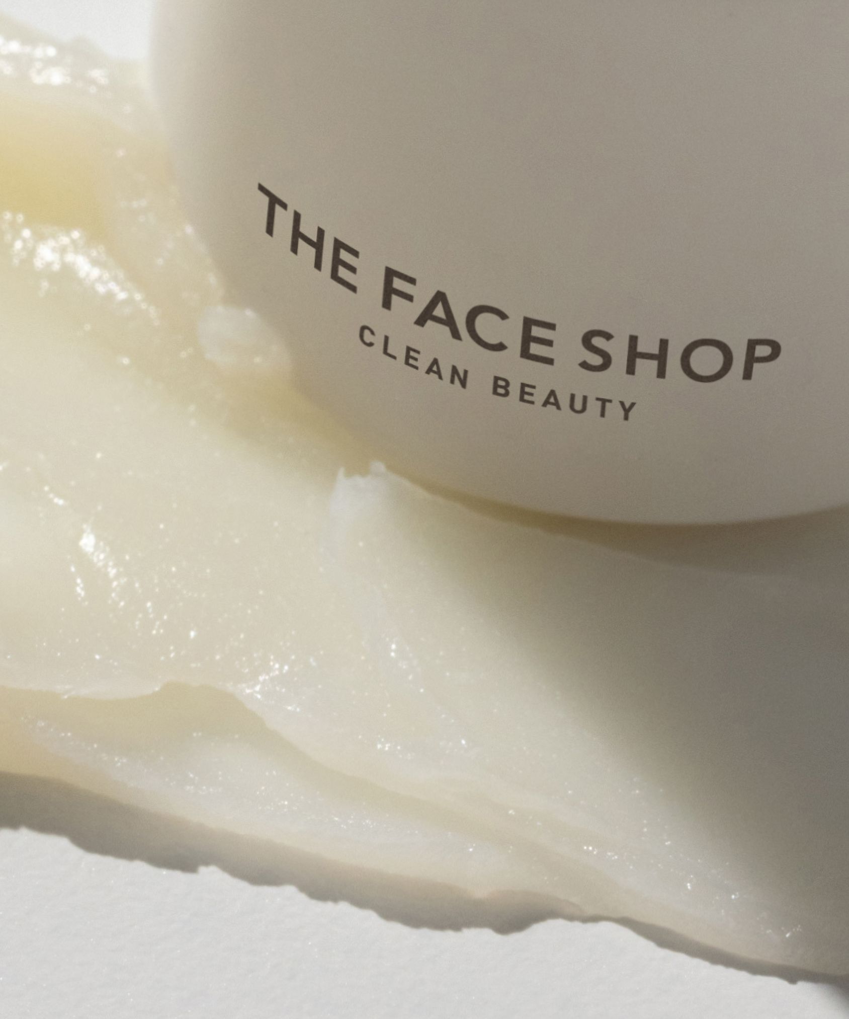 A close up of a jar of a The Face Shop moisturizing product. A smear of creamy texture is on the surface while half of the jar is out of frame.