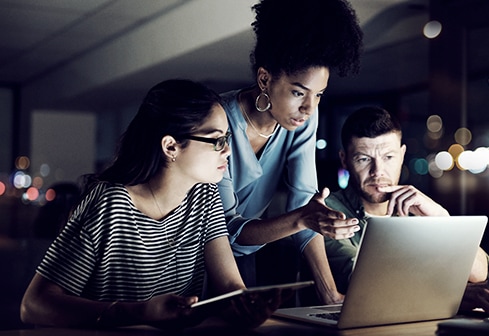 three people crowded around laptop