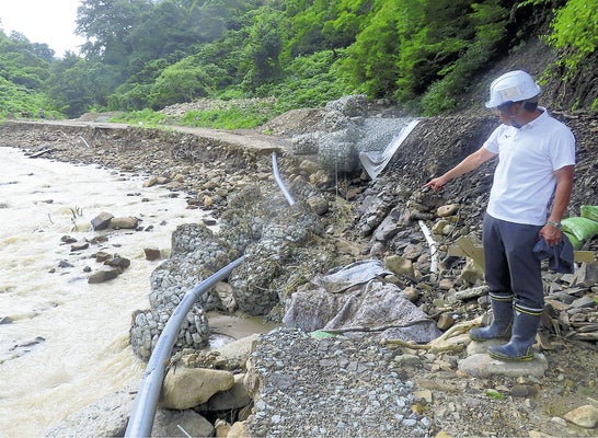 復旧工事中の町道が７月の大雨でえぐりとられ、埋められた導水管がむき出しになった（７月３０日、飯豊町萩生で）＝内田健司撮影