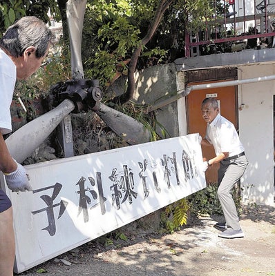 外した看板を運ぶ孝康さん（右）ら