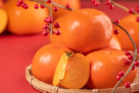 Fresh beautiful sliced sweet persimmon kaki isolated on red table ...