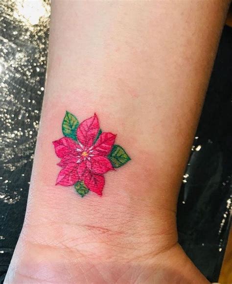 a woman's wrist with a pink poinsettia tattoo on her left arm