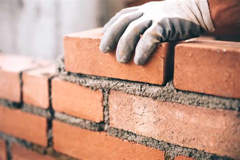 Close up of industrial bricklayer installing bricks on construction ...