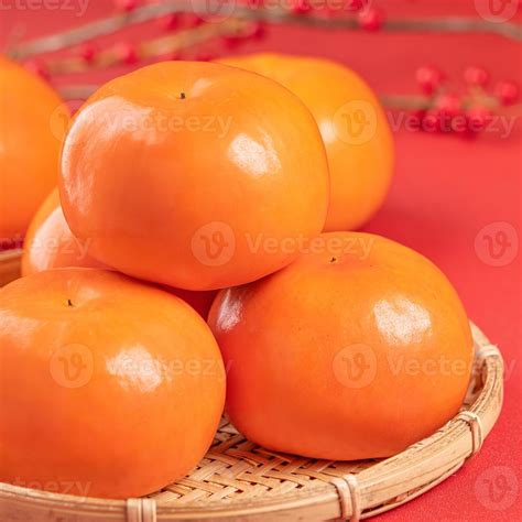 Fresh beautiful sliced sweet persimmon kaki isolated on red table ...