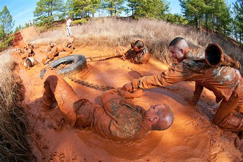 Officers help each other pull a truck tire through a mud pit during a ...