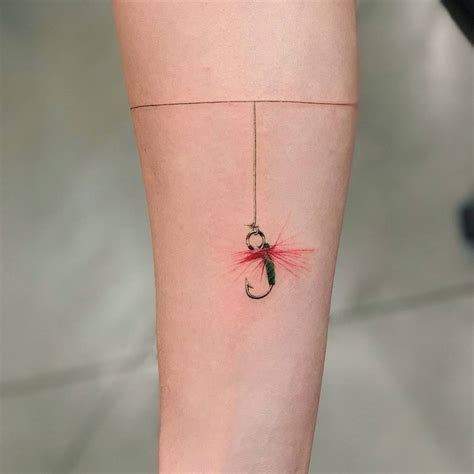 Fish hook tattoo on the inner forearm.