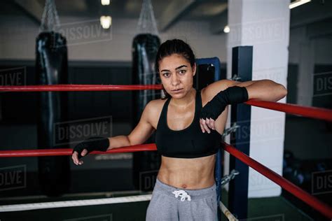 Female boxer standing inside a boxing ring with her hands resting on ...