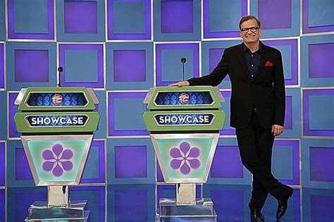 a man standing in front of two televisions on a blue stage with purple ...