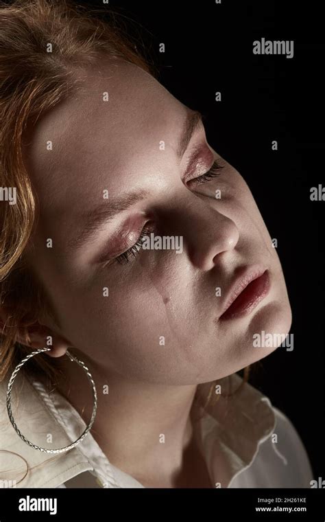 sad woman with closed eyes crying, on black background, closeup ...