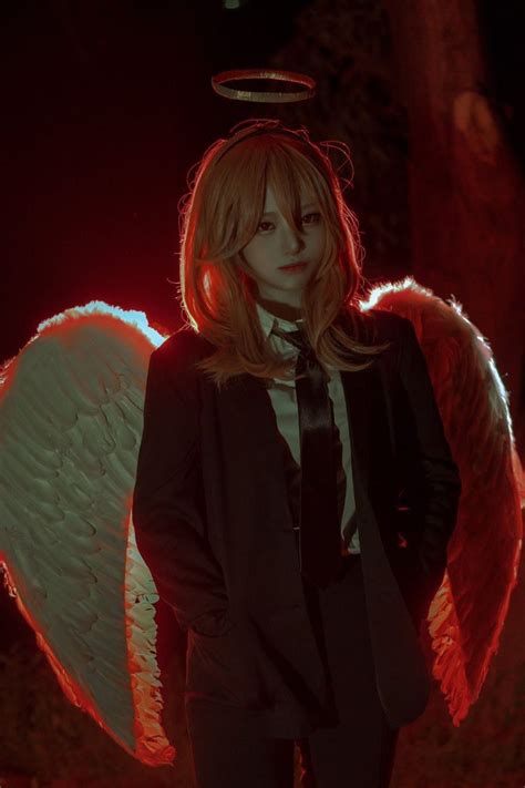 a woman in a suit with an angel wings on her head and red lights behind her