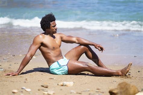 Black man in swimsuit sitting on sandy beach stock photo (272794 ...