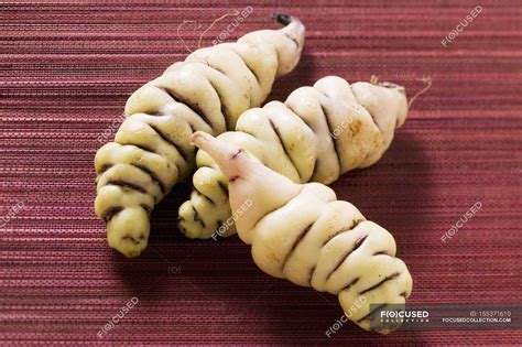 Three oca tubers - Oxalis tuberosa laying on red surface — meal ...