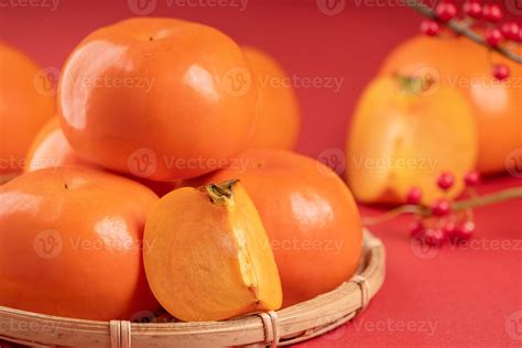 Fresh beautiful sliced sweet persimmon kaki isolated on red table ...