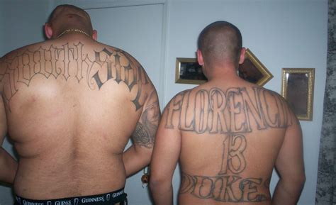 two men with tattoos on their backs standing next to each other