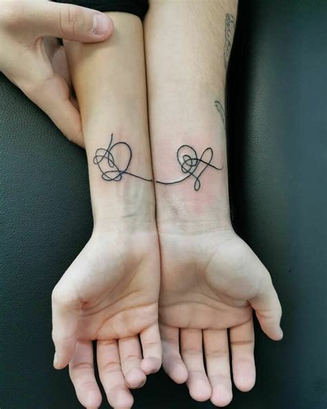 two people with matching tattoos on their arms, one holding the other's ...