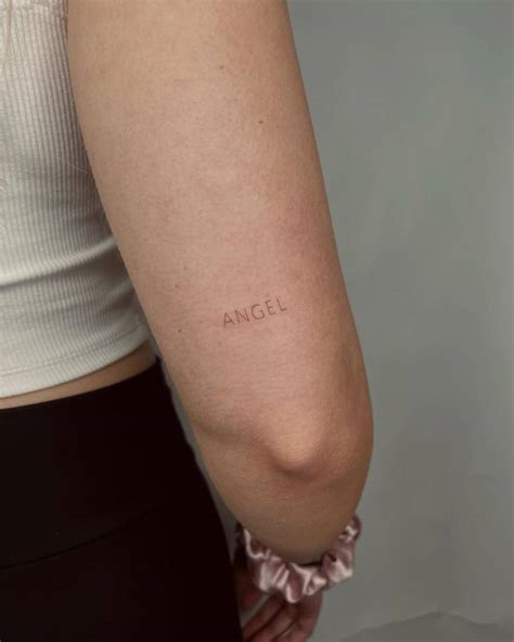 Word "angel" tattooed on the tricep.