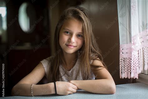 Portrait of cute ten-year-old girl posing for the camera sitting at the ...