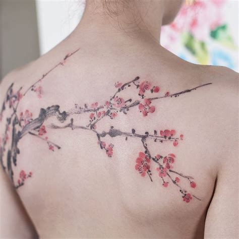 Watercolor cherry blossom tattoo on the upper back.