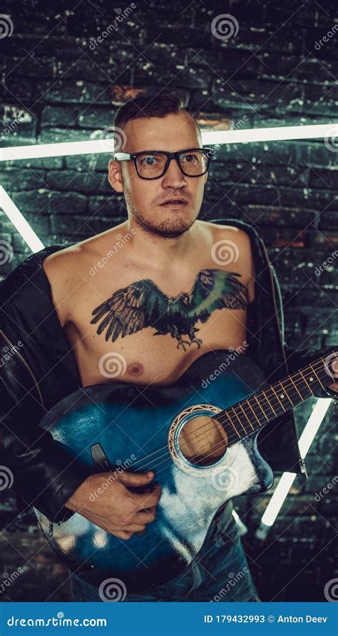 Tattooed Man Playing Guitar Near Illuminated Wall. Stylish Guy with ...